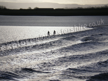 Surfers riding the Severn Bore on a fresh winters morning Surfers riding the Severn Bore on a fresh winters morning